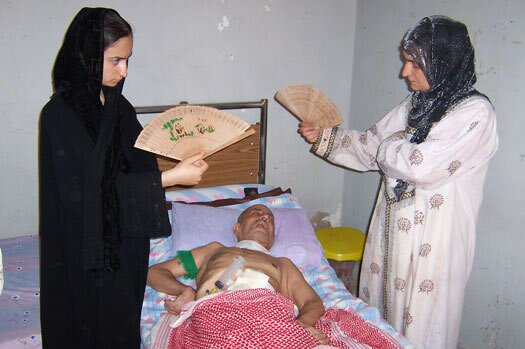 Sadiq Zoman's wife and one of 9 daughters cools him during a power outage. (Dahr Jamail/TNS)